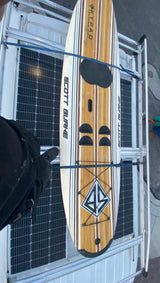 An RV rental with a Scott Burke paddleboard and solar panels on its roof rack. Perfect for outdoor adventures.