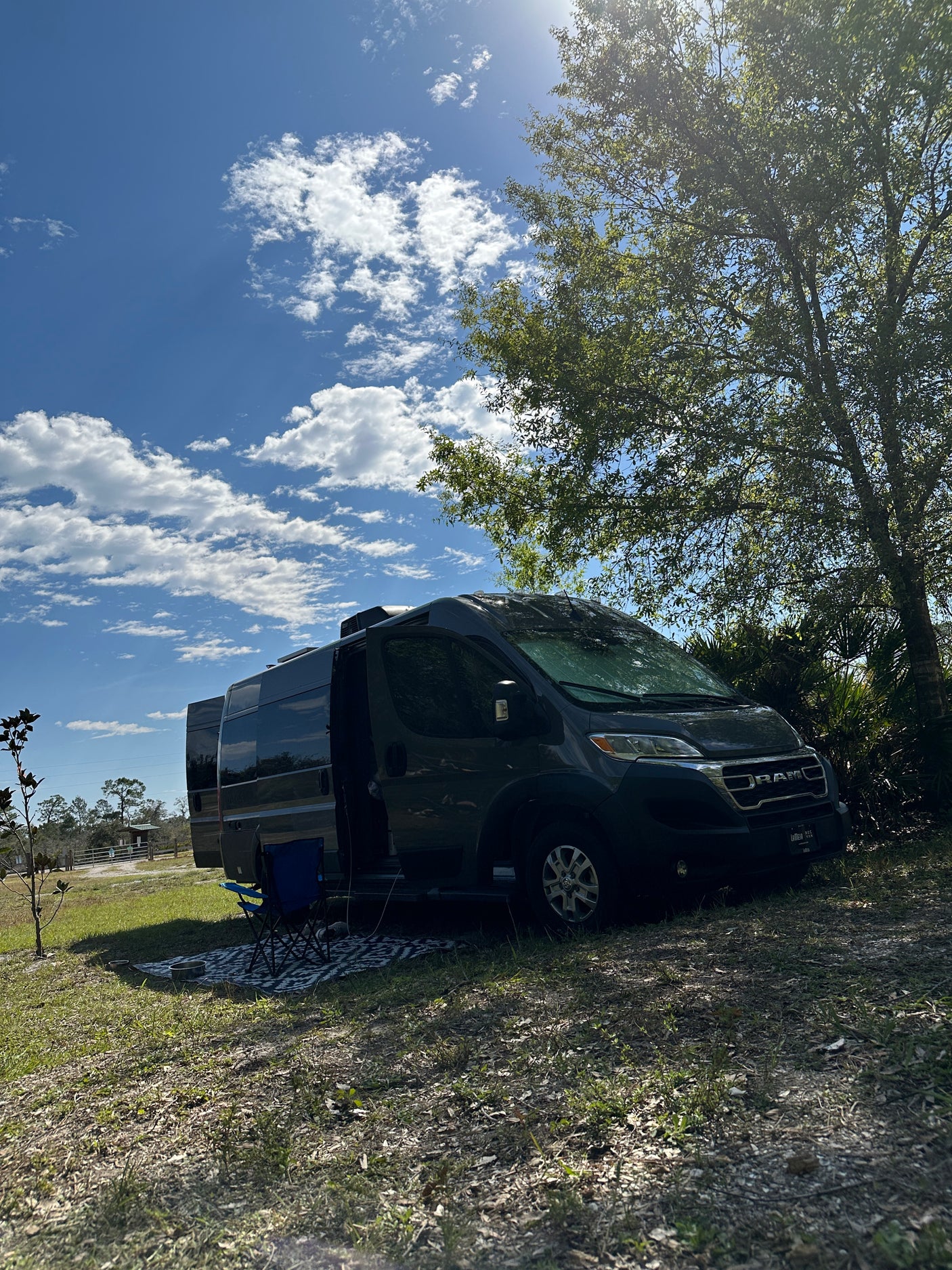 Discover freedom with an rv rental! A dark camper van parked at a sunny campsite under a blue sky.