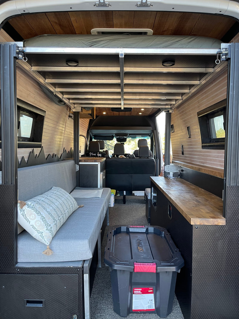 Interior of an RV rental camper van with a raised bed, comfy sofa, and wooden counter. Ready for road trips! — photo 10