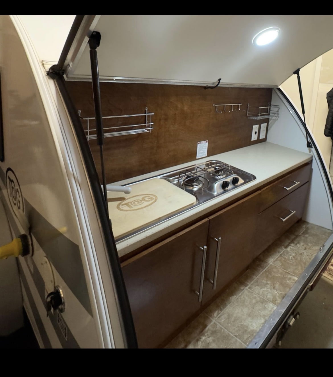  and silver SUV at dusk.|Small white RV (teardrop camper) with bikes on its front rack