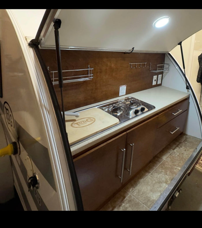 Compact T@G RV rental galley kitchen with stove, sink, and cabinets. Perfect for outdoor cooking on your next trip.