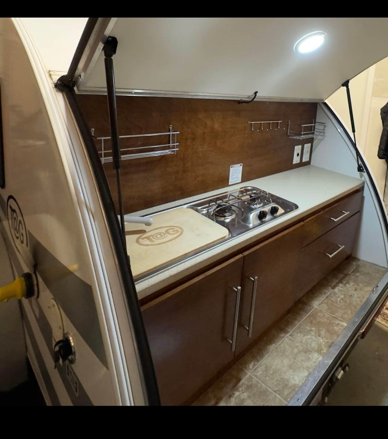  and silver SUV at dusk.|Small white RV (teardrop camper) with bikes on its front rack — photo 1