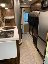 Experience RV rental comfort: detailed view of a compact kitchen, folded bed, and clever storage solutions.