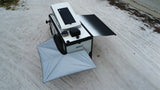 Overhead view of an EKKO off-road RV rental with deployed awnings on a sandy beach. Solar panel visible.