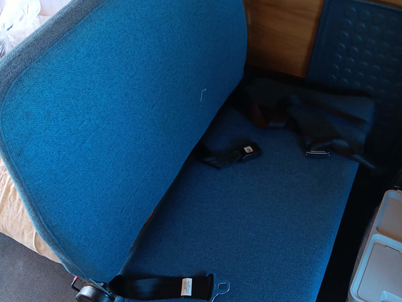 RV rental interior: Blue upholstered bench seat with seatbelts, its back folded down for versatile space. — photo 6