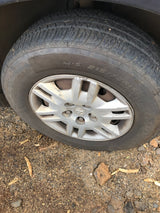 All-season tire (M+S 215/70R15) of an rv rental parked on dirt; silver wheel is scuffed.