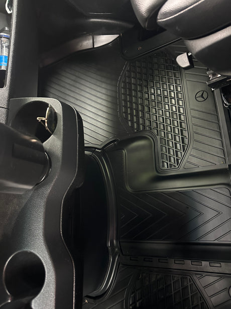RV rental interior: black rubber floor mats with Mercedes-Benz logo, showing a clean passenger footwell and cup holder.