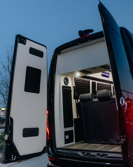Open rear of a luxury Mercedes-Benz Sprinter van for RV rental, showing custom interior, quilted seats & ambient lighting.