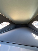 RV rental interior: Light fabric pop-up roof, mesh windows, and a large dark sleeping platform in this camper.