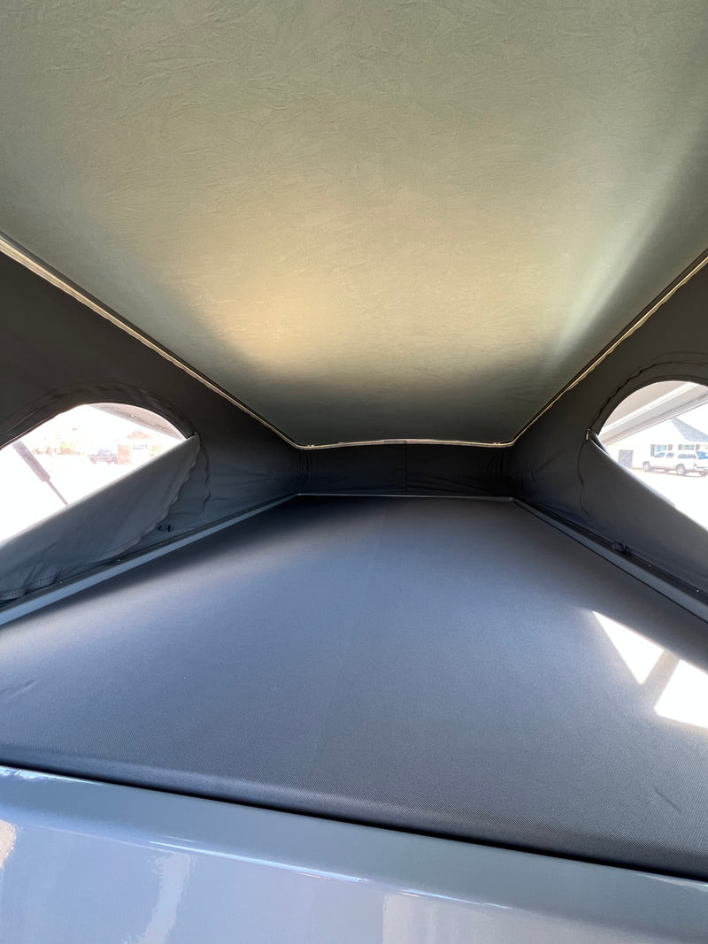 RV rental interior: Light fabric pop-up roof, mesh windows, and a large dark sleeping platform in this camper. — photo 7