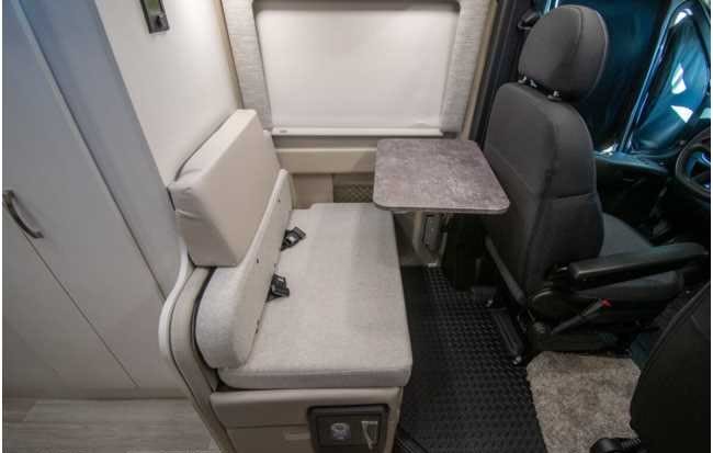 RV rental interior: cozy dinette with bench seat, table, and swiveling driver's seat.