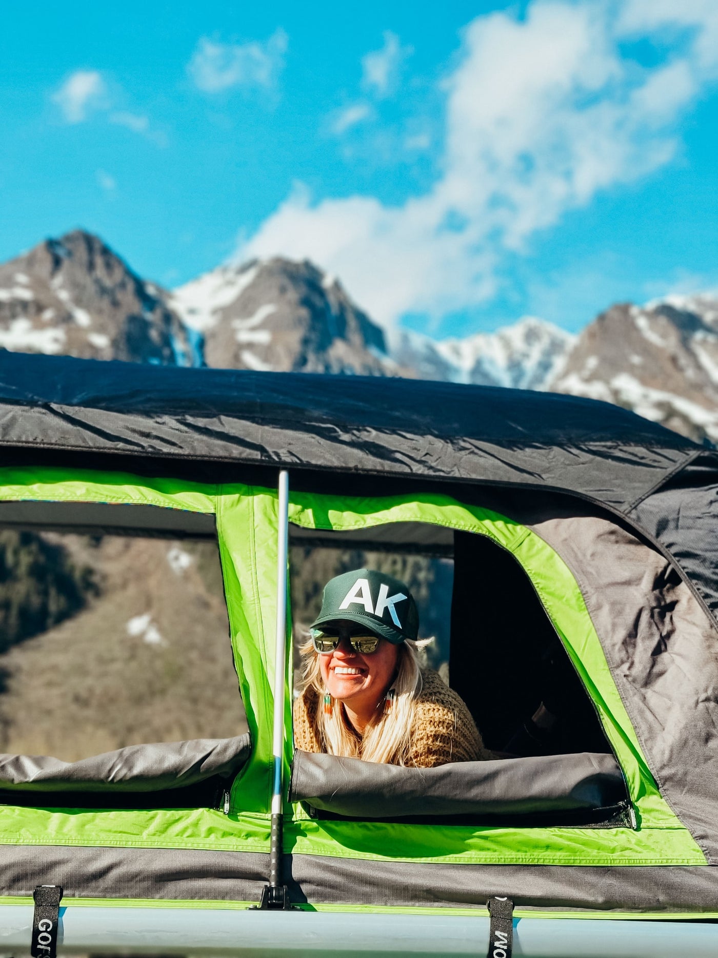 Smiling woman in an RV rental rooftop tent enjoys majestic mountain views on a sunny day. — photo 7