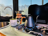 Enjoying the morning brew in an RV rental kitchen. Coffee, gas stove, and mountain views mean adventure begins!