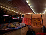 Cozy, customized RV rental interior with wood paneling, string lights, and a charming kitchenette, ready for road trips.