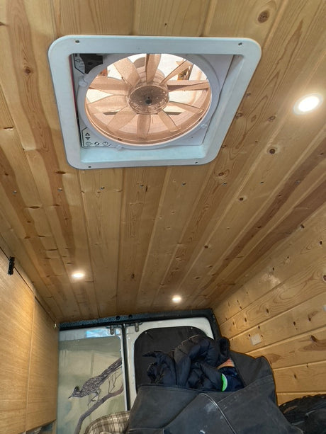 RV rental interior showcasing a wood-paneled ceiling with a vent fan, LED lights, and unique roadrunner art at the back.
