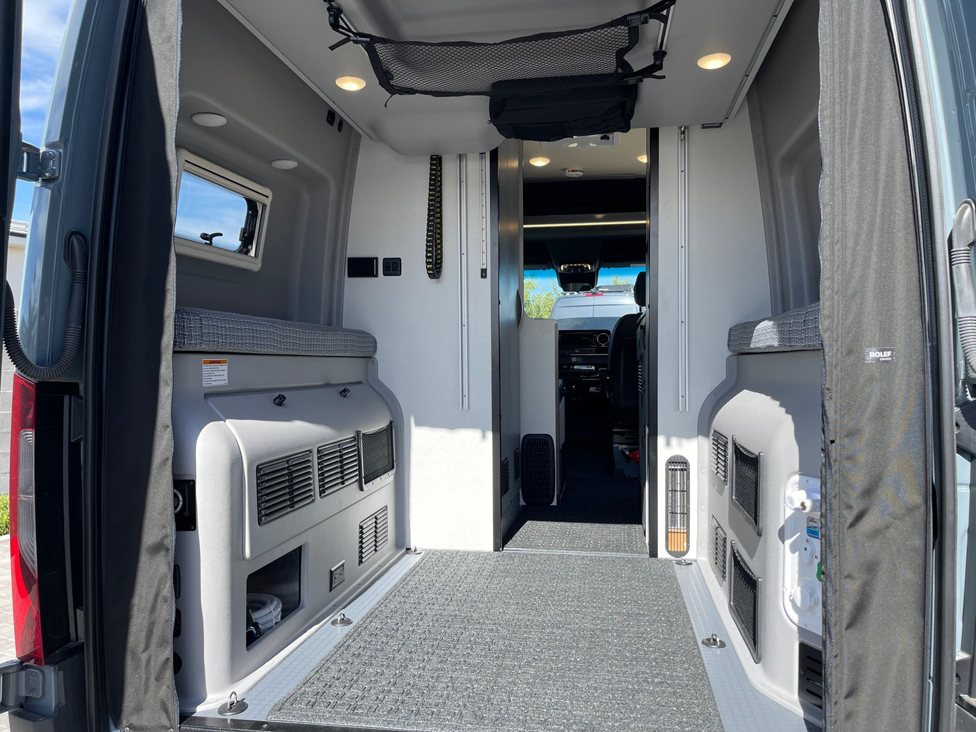 Spacious RV rental interior from the rear, showing versatile storage, seating, and a clear path to the front cabin.