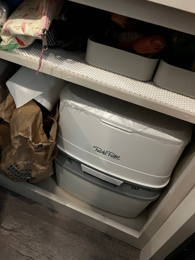Inside an RV rental: Porta Potti 365 portable toilet, toilet paper, and personal items neatly stored in a cabinet. — photo 20