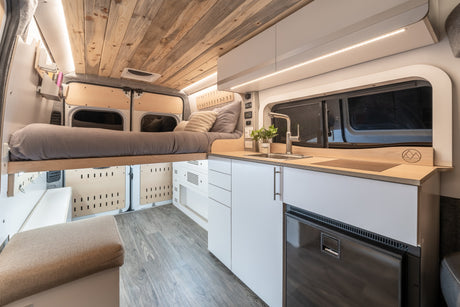 Explore a cozy, well-designed camper van interior, perfect for your next rv rental adventure. Features bed, kitchen, and warm lighting.