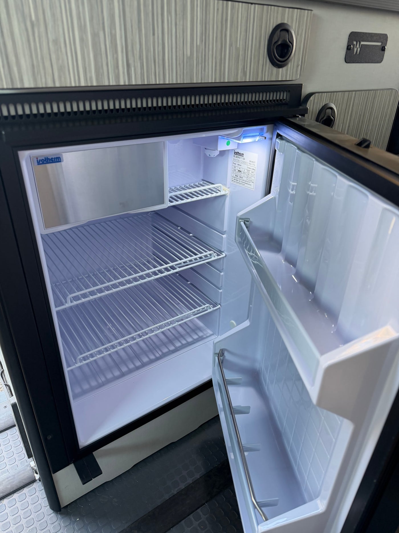Open Isotherm refrigerator in an RV rental, showing wire shelves and freezer. Essential for your camper van kitchenette. — photo 7