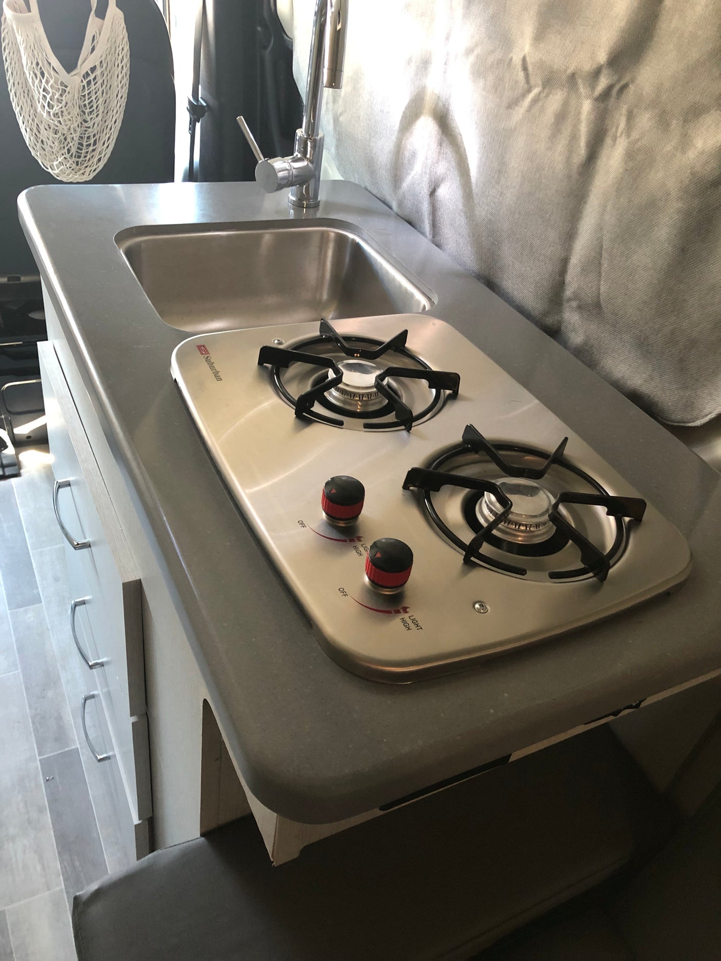 Compact rv rental kitchen: built-in sink with faucet & two-burner Suburban stove. Ideal for on-the-go cooking.