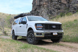 White Ford F-150 truck with overland gear, ready for your next rv rental adventure on a scenic dirt road.