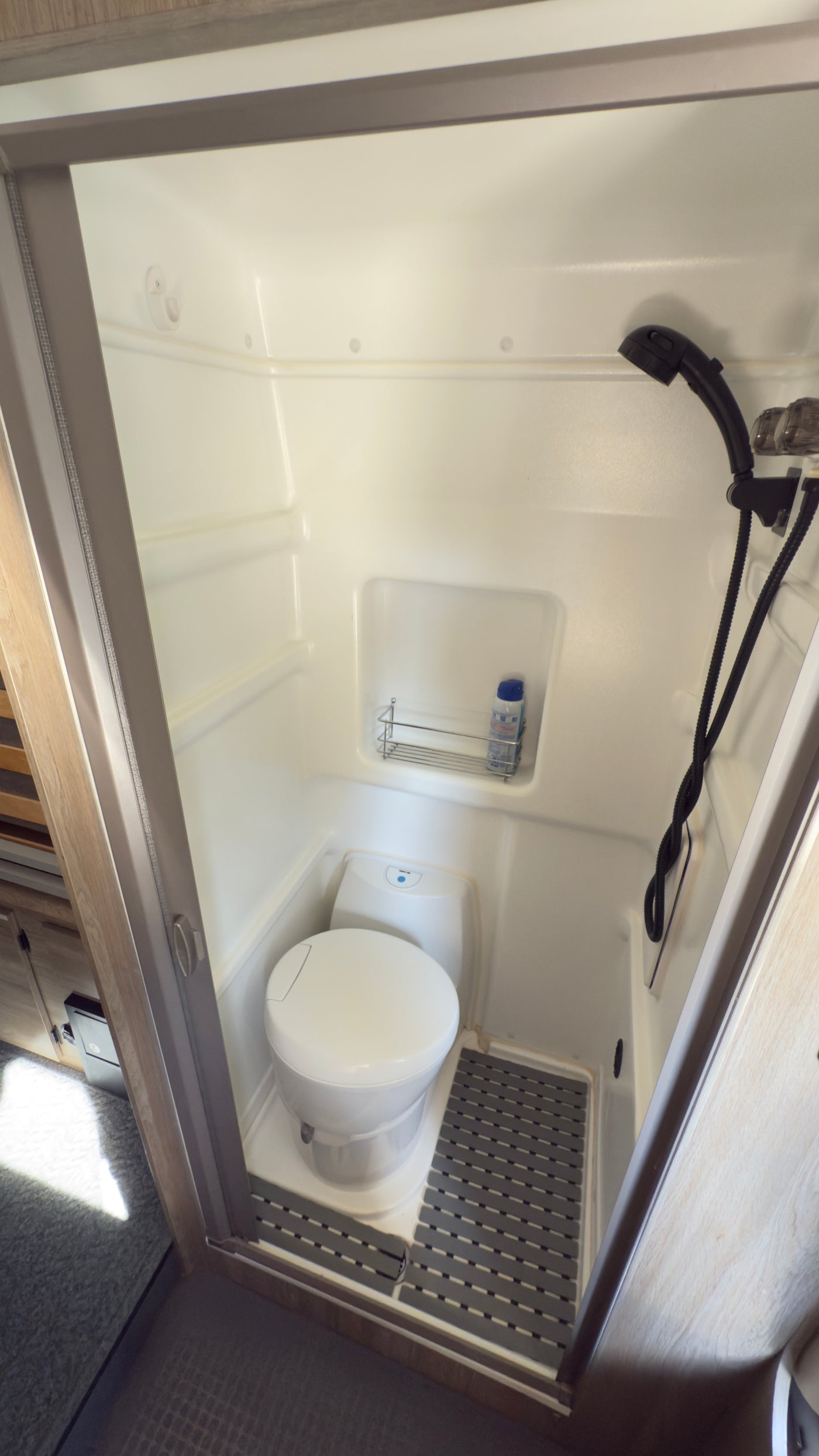 An RV rental's compact wet bath, featuring a toilet, shower, and non-slip mat for efficient travel. — photo 11