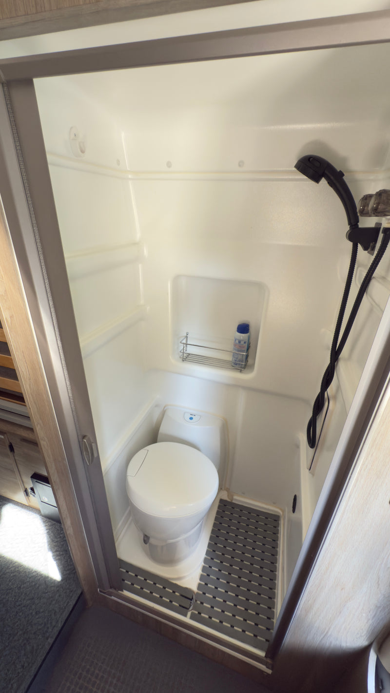 An RV rental's compact wet bath, featuring a toilet, shower, and non-slip mat for efficient travel. — photo 11