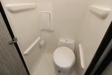 See inside an RV rental! This compact, all-white RV bathroom features a toilet, toilet paper holder, and wall-mounted cabinet.