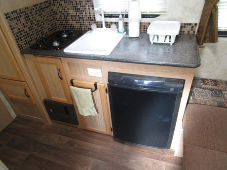 Explore this RV rental's galley: compact kitchen with stove, sink, Dometic fridge, and storage.