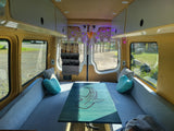 Spacious RV rental interior with custom seating, whale shark table, and cozy lighting. Perfect camper van setup!