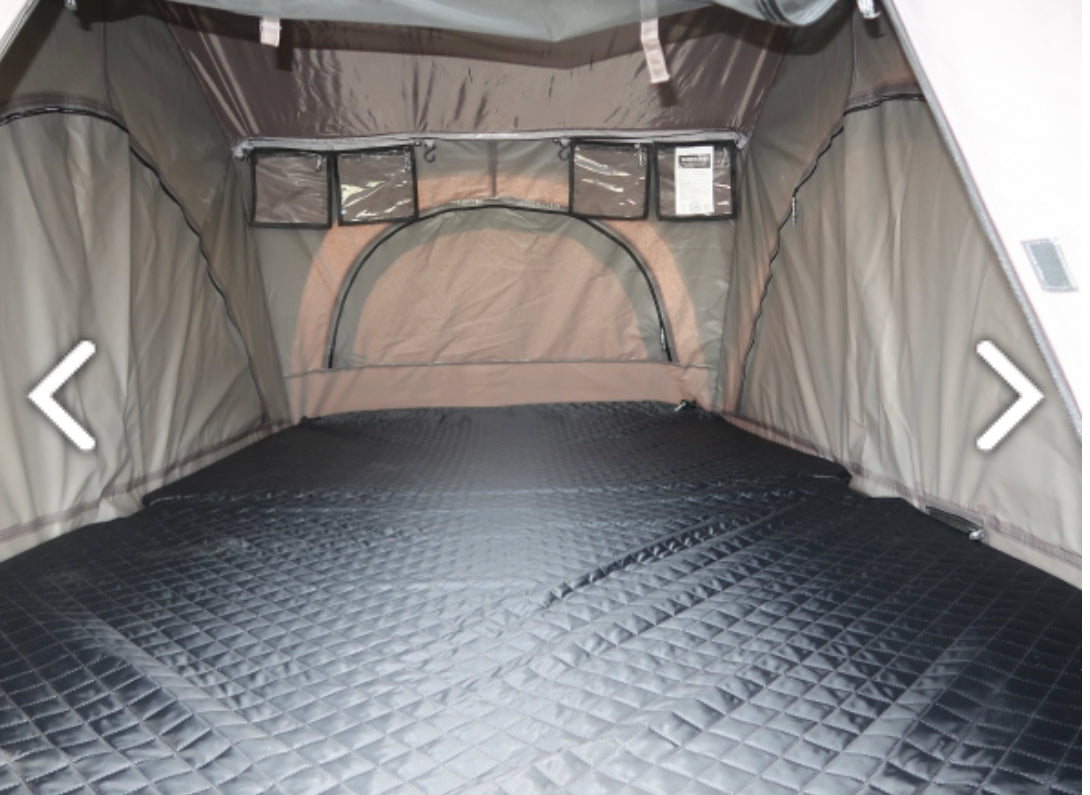 RV rental: Inside a spacious rooftop tent with a quilted sleeping pad, clear storage pockets, and arched window.