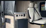 Modern RV rental interior: integrated fridge, power outlets, and plush passenger seating for your journey.