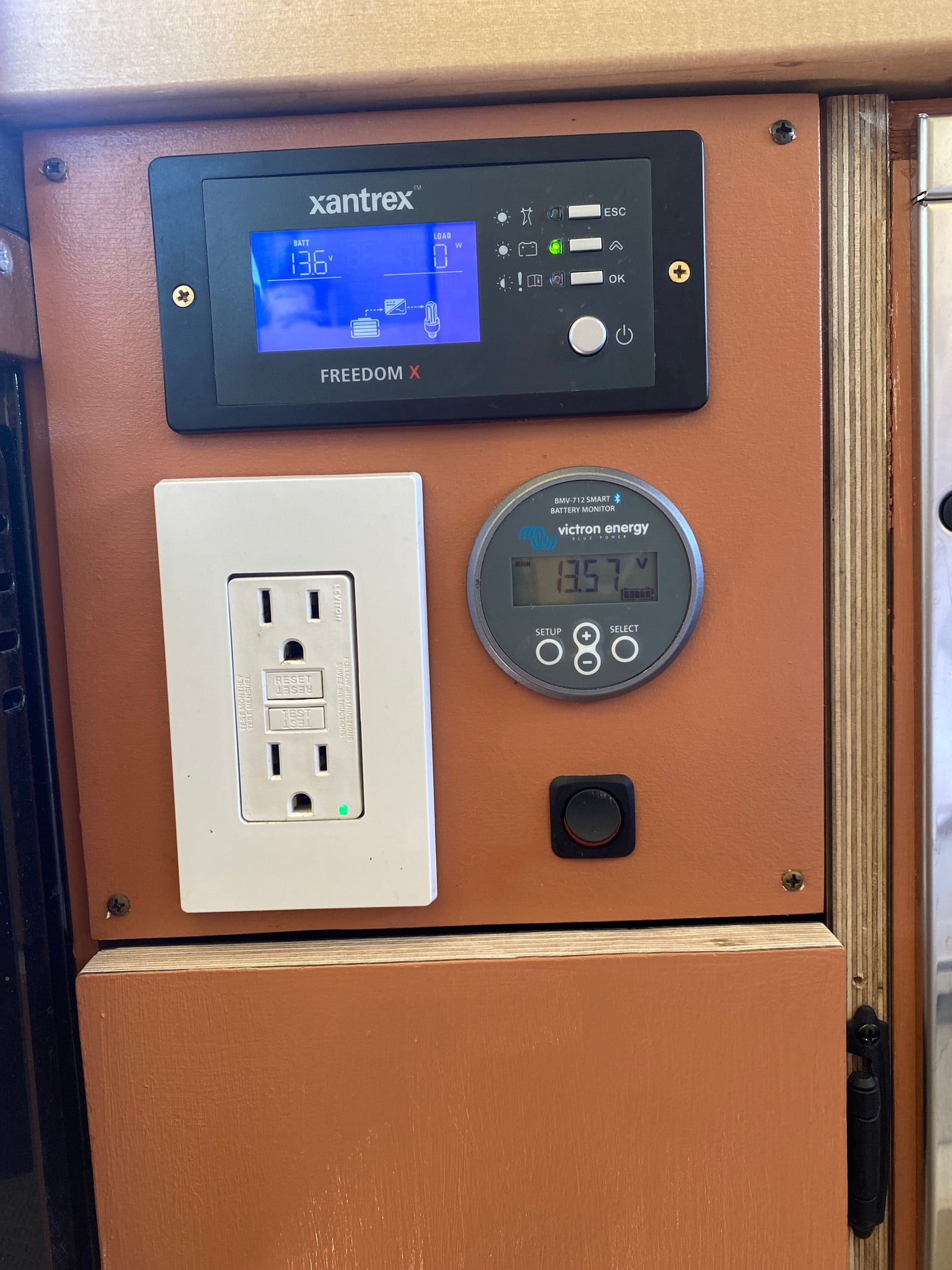 RV rental power control panel: Xantrex inverter, Victron battery monitor showing 13.57V, and a GFCI outlet for off-grid power.