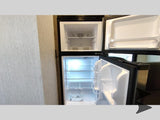RV rental: Open compact refrigerator/freezer in an RV, ready for your trip's essentials.