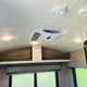 RV rental interior featuring a central AC unit, bright LED lights, and netted overhead storage above a window.