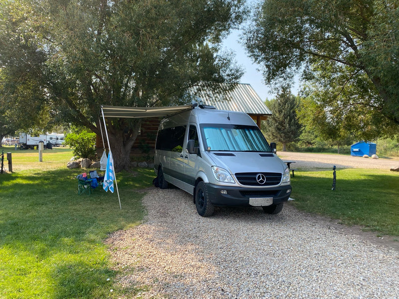 Silver Sprinter rv rental campervan set up for outdoor living at a peaceful campground — photo 1