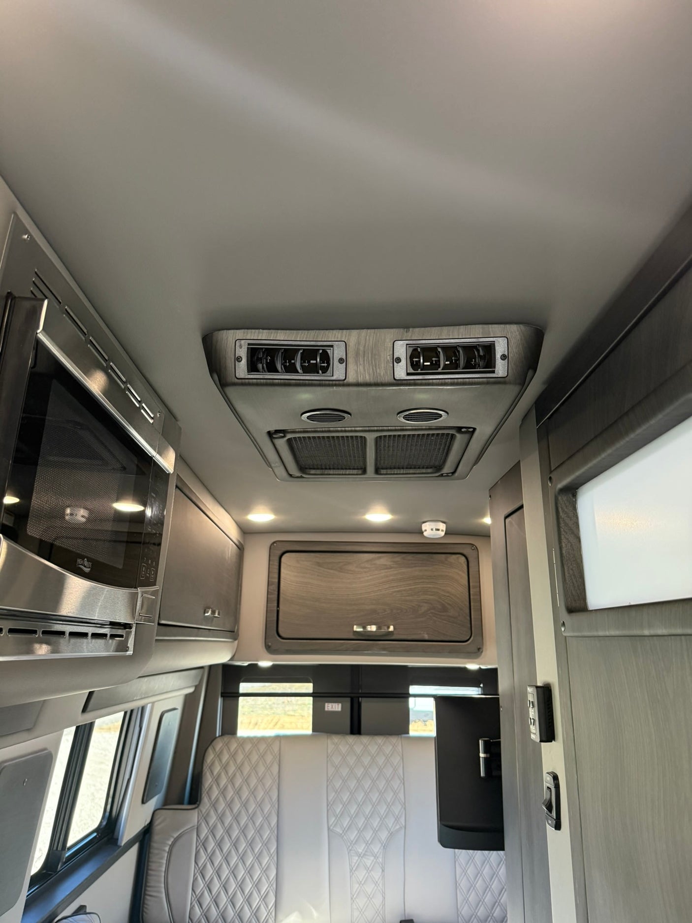 Experience our rv rental interior: microwave, AC, quilted seating, and sleek cabinetry for your van adventure.
