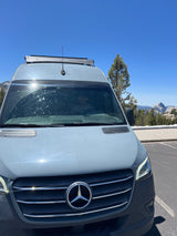 A grey Mercedes-Benz Sprinter RV rental parked, featuring a Westin roof rack, with Yosemite's iconic Half Dome in the background.