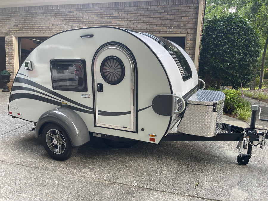 This white teardrop RV rental, with a distinct rounded design and diamond plate storage box, is ready for your next trip.