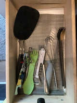 Essential kitchen tools for your RV rental: spatula, whisk, can opener, corkscrew, and cutlery neatly arranged in a lined drawer.