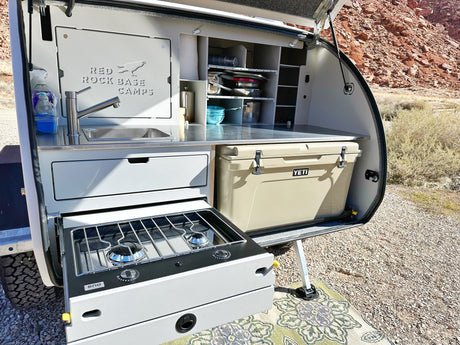 Explore the convenience of an rv rental! This compact camper's outdoor kitchen features a sink, stove, & Yeti cooler.