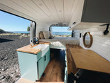 Experience van life! This RV rental features a cozy bed, kitchen, and panoramic ocean views from inside a modern camper.