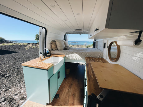 Experience van life! This RV rental features a cozy bed, kitchen, and panoramic ocean views from inside a modern camper.