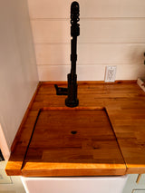 RV rental kitchen features a light wood counter, modern black faucet, and a smart, covered sink design.