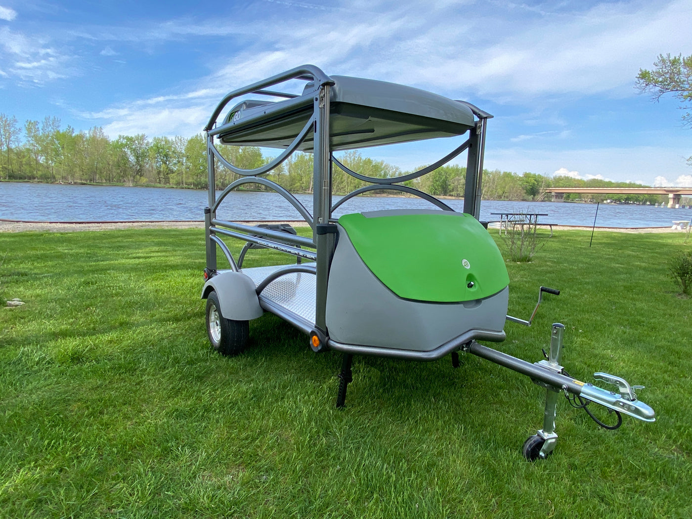 Small, modern trailer for RV rental, parked on green grass by a lake. Designed for efficient outdoor adventures & travel. — photo 3