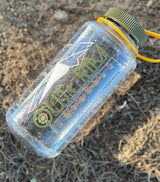 Clear OUTRIV Adventure Rentals water bottle, a must-have for any RV rental or outdoor adventure. Resting on dry ground.