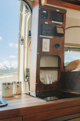 RV rental: Compact kitchen with induction cooktop, control panel, power outlets, and stunning mountain views out the door.