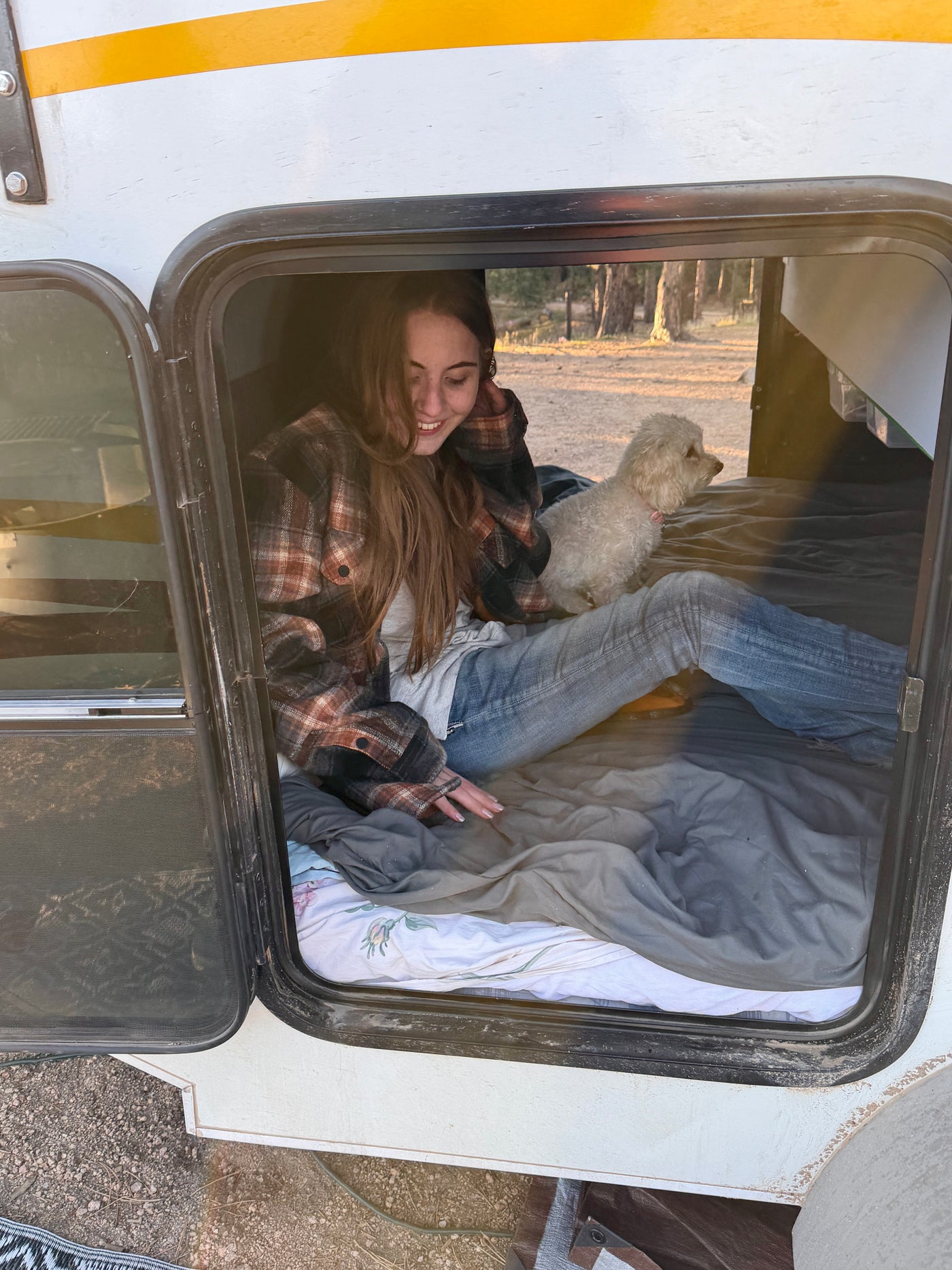 A smiling woman and her fluffy white dog relaxing inside a cozy RV rental. Perfect for outdoor adventures. — photo 10