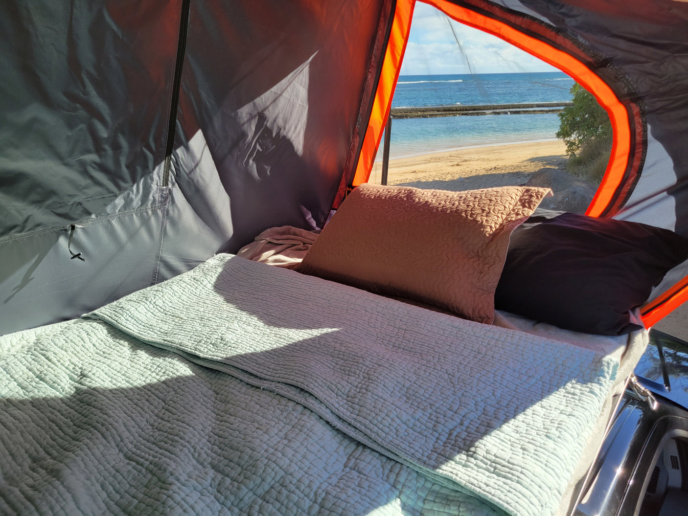 RV rental comfort: a cozy bed inside a tent with a beautiful beach and ocean view. Perfect for a serene coastal escape.