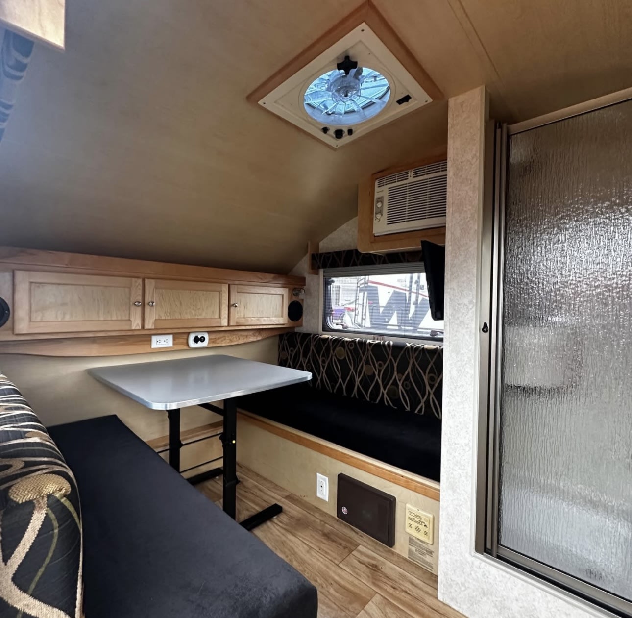 Cozy RV rental interior with dinette, cabinets, AC, and shower stall. Perfect compact living space for travel. — photo 10